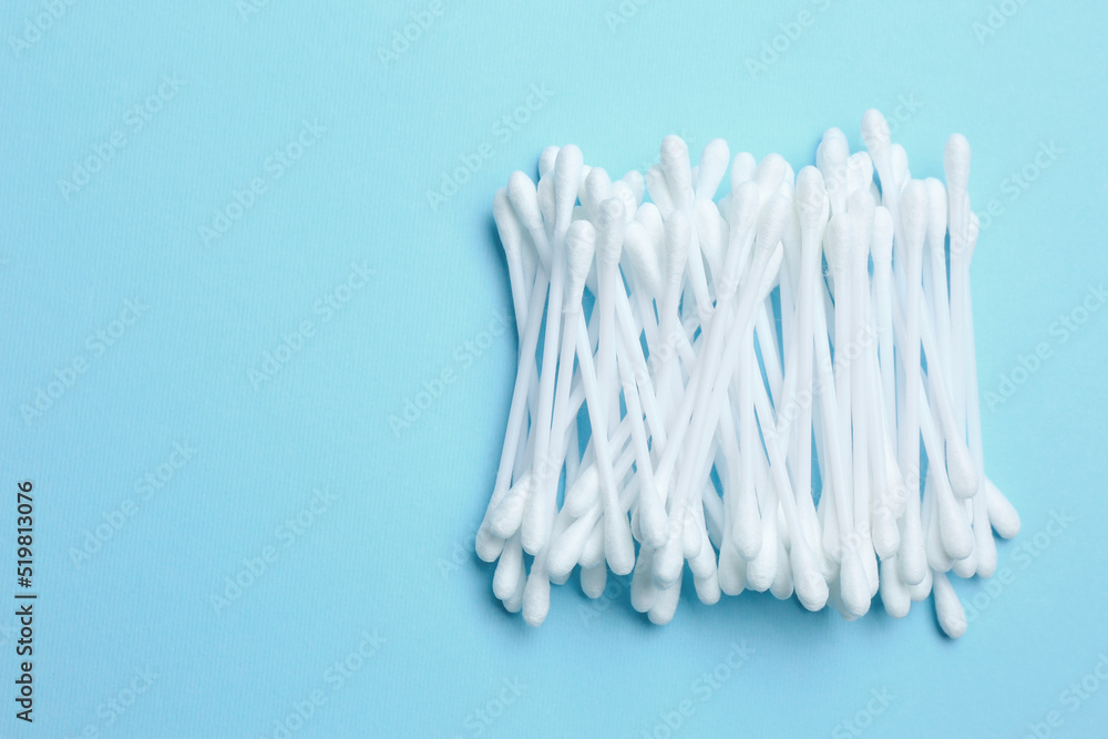 Heap of cotton buds on light blue background, top view. Space for text Heap of cotton buds on light blue background, top view. Space for text