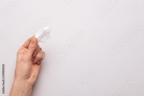 Woman holding anti-snoring device on light grey background, top view. Space for text