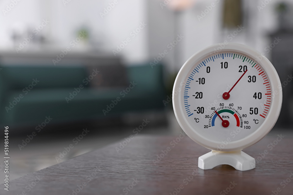 Round mechanical hygrometer on wooden table in room. Space for text - obrazy, fototapety, plakaty 