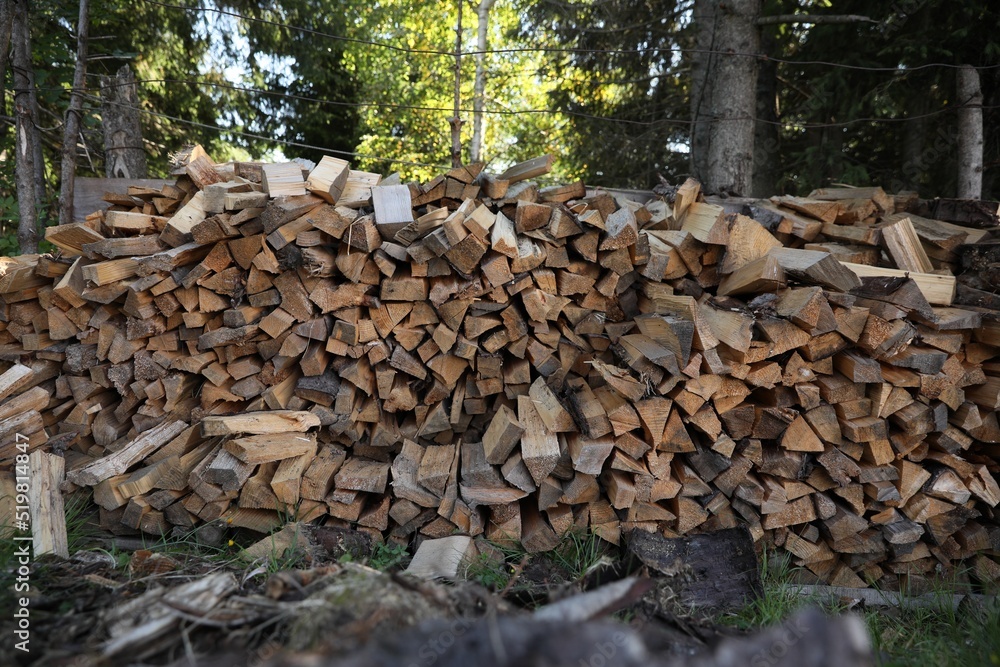 Stack of cut firewood on green grass outdoors. Heating in winter