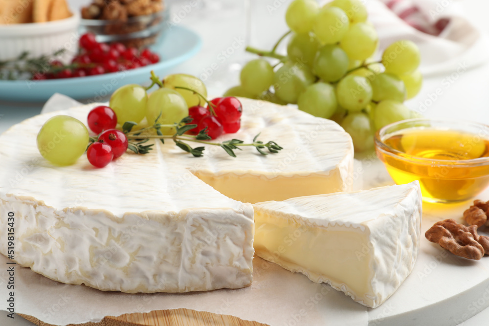 Brie cheese served with honey and berries on white table, closeup