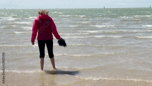 (SLO-MO) Woman walking on the beach of Sanlucar de Barrameda in Spain, at the mouth of the Gualdalquivir River in the Atlantic Ocean and with the 'Coto Doñana' National Park in front. photo