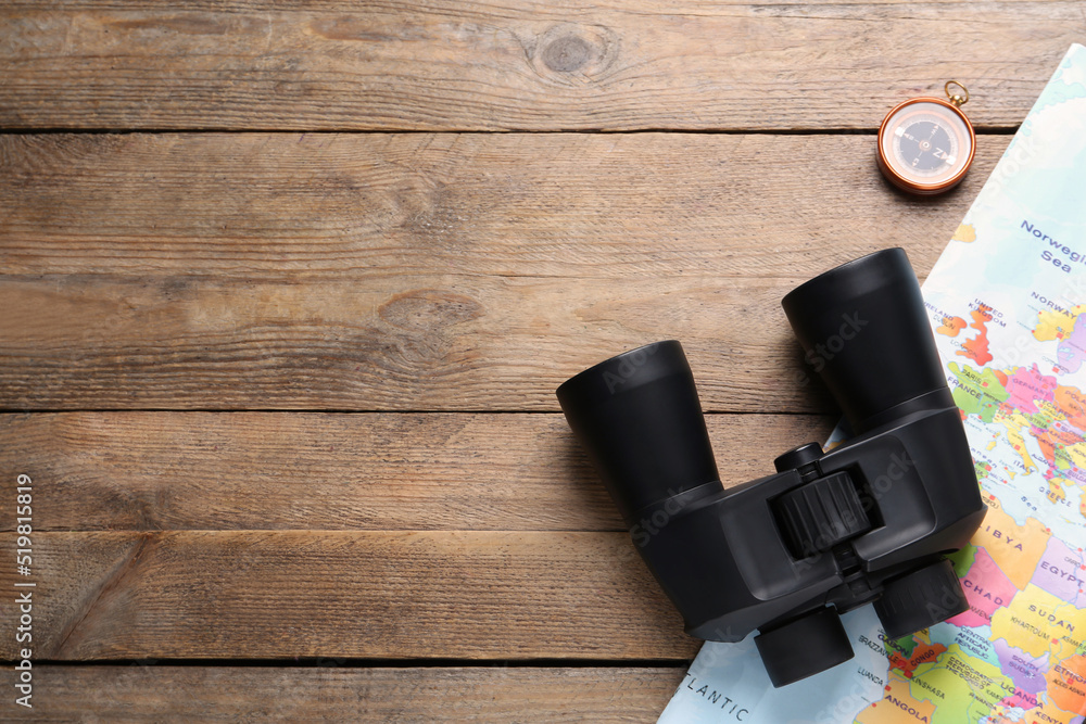 Modern binoculars, map and compass on wooden table, flat lay. Space for text Modern binoculars, map and compass on wooden table, flat lay. Space for text