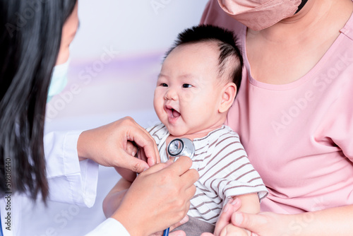 Woman doctor wearing surgical masks and using a stethoscope  checking the respiratory system and heartbeat Of a 3-months-old baby newborn  to baby newborn and  health care concept.