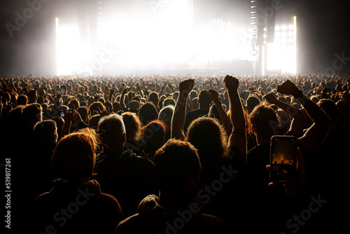 People with raised hands at a music concert. Fans in concert hall.