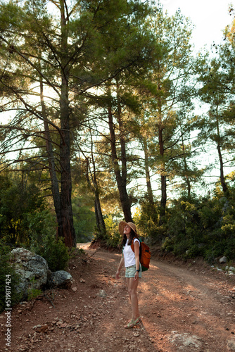 a traveler girl with a backpack walks along a forest road.