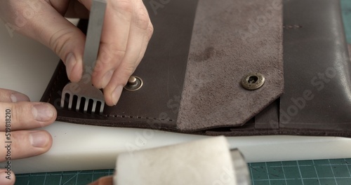 A man makes a handmade leather wallet from genuine leather.