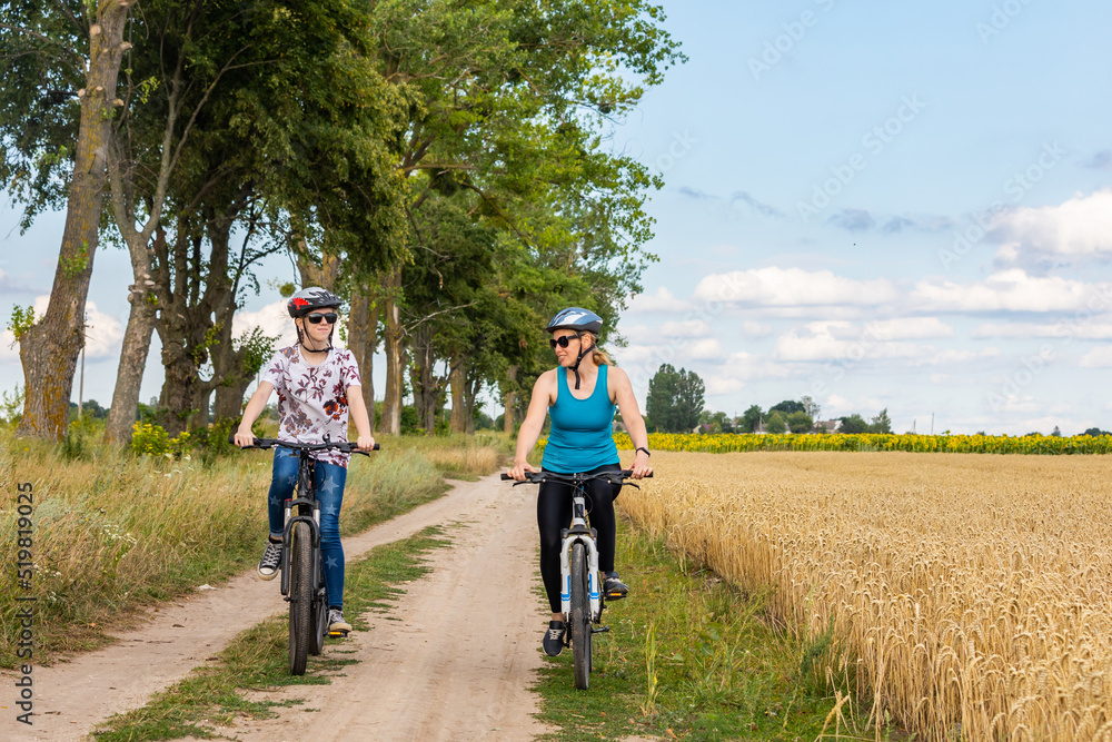 family bike ride. Mather and daughter and riding mountain bike in summer meadow on a sunny day.