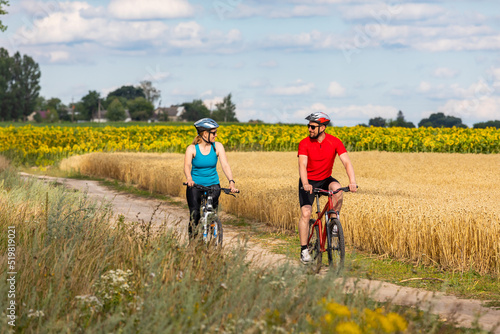 Young cheerful biker couple riding mountain bike in summer meadow on a sunny day