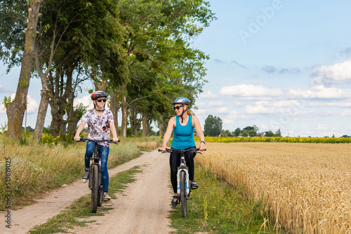 family bike ride. Mather and daughter and riding mountain bike in summer meadow on a sunny day.