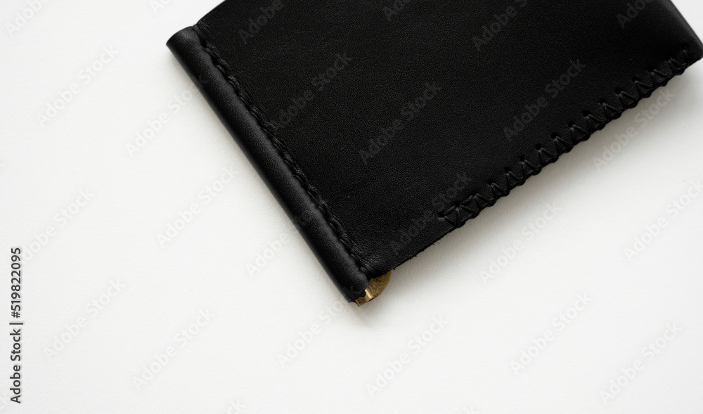 Black men's money clip handmade leather wallet for cards lies on a white table. Leather goods and accessory. Black men's money clip handmade leather wallet for cards lies on a white table. Leather goods and accessory.
