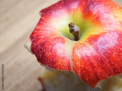 Red apple core on a wooden background. A bitten apple close-up.