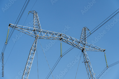 Fragment of metal pole of high-voltage power line VL-750 kV against blue sky. Close-up. There are more than 20 insulators in garland. Garlands of insulators are made of glass.