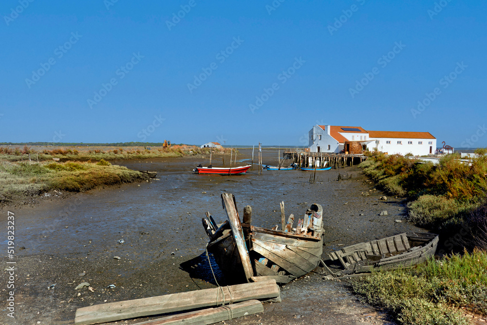 wreck and colorful boat lying on the mud at low tide near Setubal, Portugal