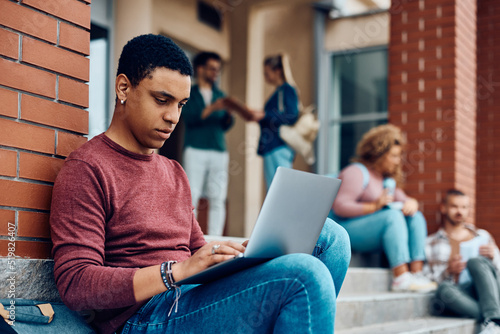 Photos Young black student e-learning on laptop at campus.