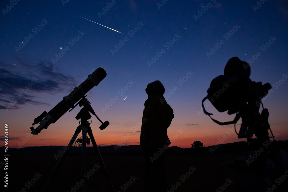 Man with astronomical telescope observing night sky, under the Milky way stars.