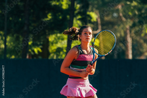 Young female tennis player hitting the ball to the ground with a racket while waiting for the tennis game to start © qunica.com