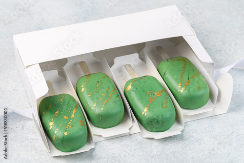 Greeen cake pops, popsicles in white box. Sweet concept. White background.