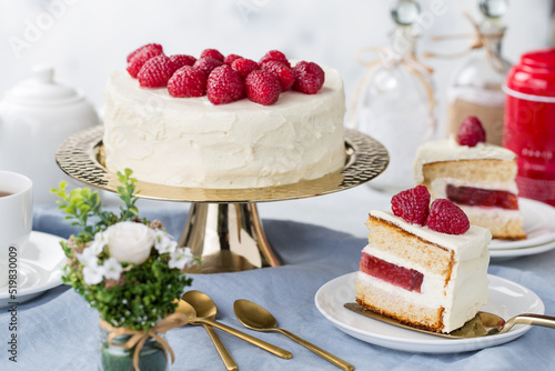 White cake with a wreath made of raspberries on the white background