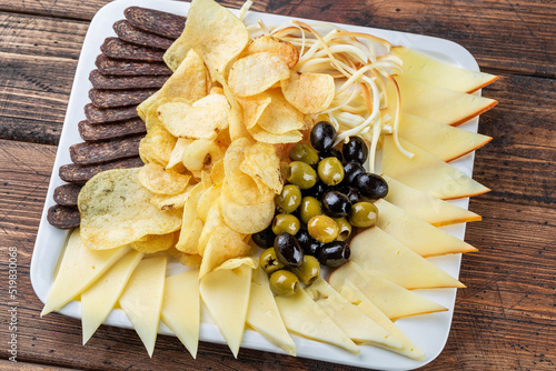 snacks on a wooden tray, sausage, chips, cheese, Assortment of beer snacks, dried meat, smoked cheese and sausage on wooden background. Beer Snack Mix plate for oktoberfest photo