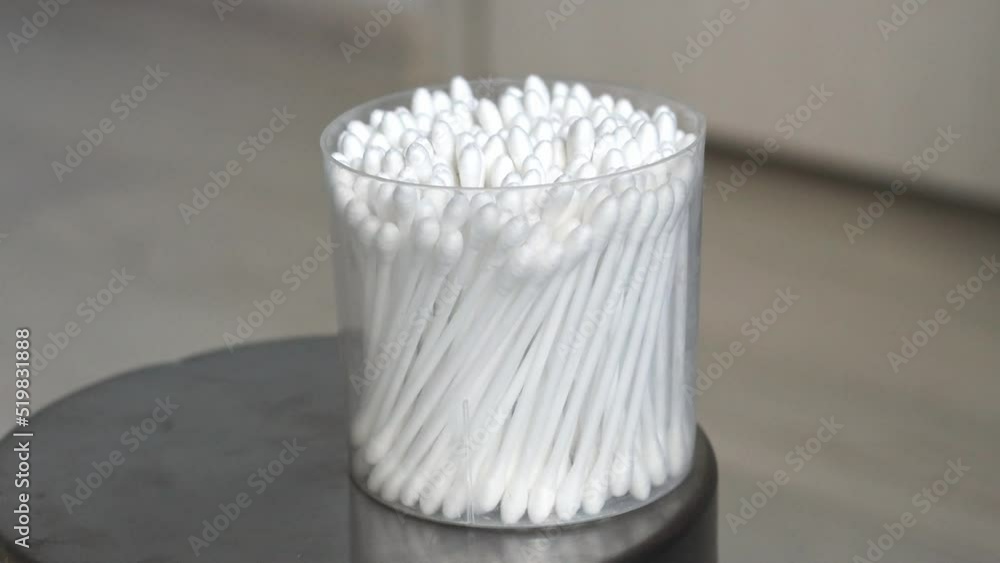 The girl puts a glass with cotton swabs