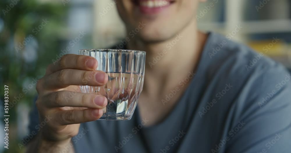 Young man drinks a glass of water	