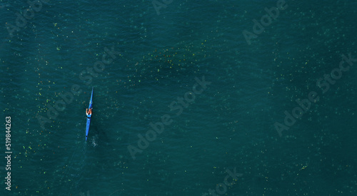 Drone view of sport kayak on the lake operated young sports man. Aerial lake with blue water and canoe. Healthy lifestyle, hobby