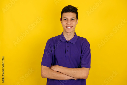Close-up portrait of a young man, a teenager on a yellow background, smiling beautifully at the camera