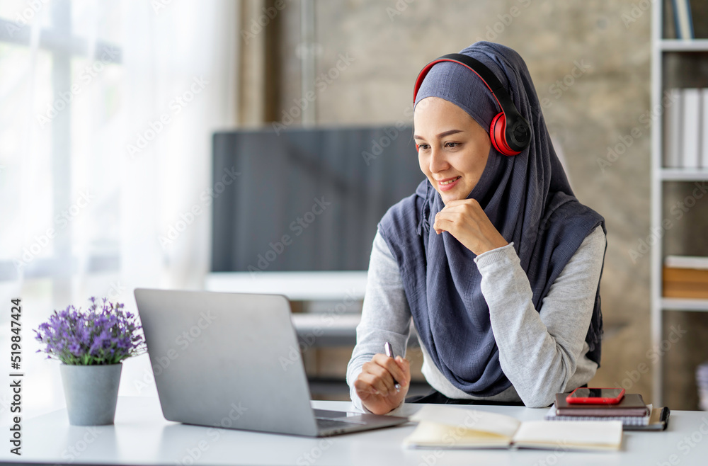 Muslim businesswoman wearing a hijab looks at camera working Online Tutoring. Young Muslim woman teacher having a video call with students Muslim businesswoman wearing a hijab looks at camera working Online Tutoring. Young Muslim woman teacher having a video call with students