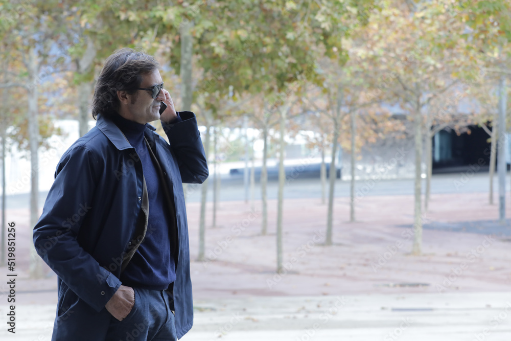 Fototapeta premium happy businessman walking outdoors with mobile phone.