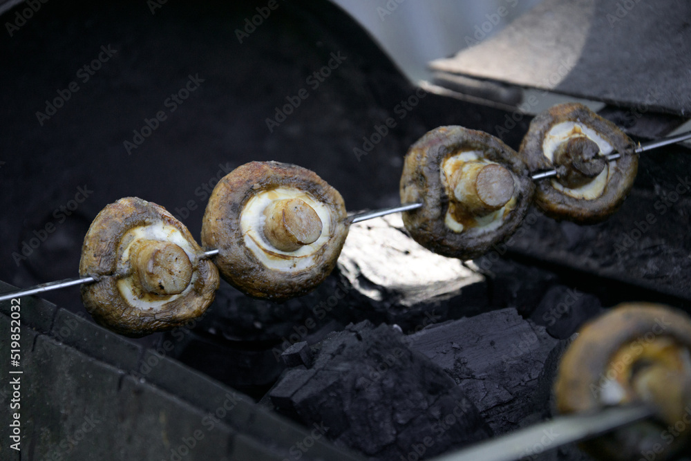 White mushrooms champignons are planted on skewers lie on the grill White mushrooms champignons are planted on skewers lie on the grill