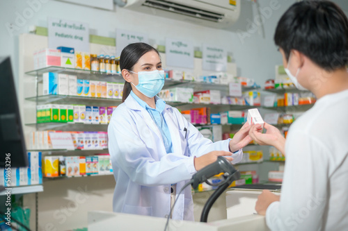 Portrait of female pharmacist wearing face mask in a modern pharmacy drugstore.