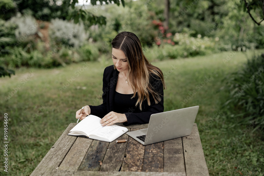 Obraz premium Geschäftsfrau arbeitet in freier natur auf einem Laptop am Holztisch
