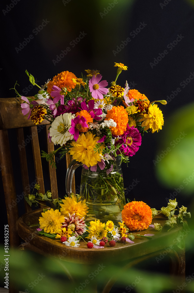 Gorgeous summer still life with a bouquet of multi-colored garden and wild flowers on a black background with a blurred bokeh of greenery Gorgeous summer still life with a bouquet of multi-colored garden and wild flowers on a black background with a blurred bokeh of greenery