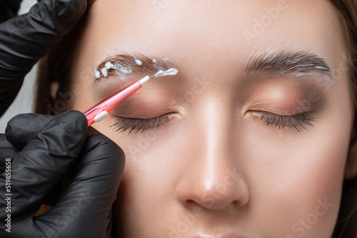The make-up artist does Long-lasting styling of the eyebrows of the eyebrows and will color the eyebrows. Eyebrow lamination. Professional make-up and face care. photo
