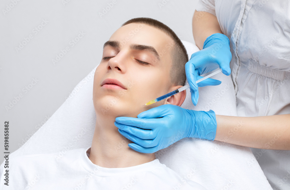 Men's cosmetology. Beautician makes a man a rejuvenation injection procedure of a handsome young man in a beauty salon. Men's cosmetology. Beautician makes a man a rejuvenation injection procedure of a handsome young man in a beauty salon.