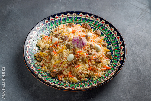 pilaf with beef, eggs, carrot on beautiful uzbek plate