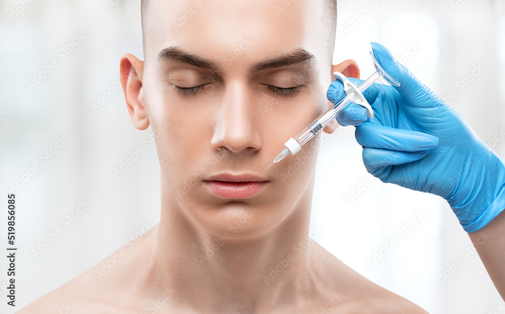The cosmetologist makes injections for lip augmentation and anti-wrinkle in the nasolabial folds of a man. Male cosmetology in a beauty salon. The cosmetologist makes injections for lip augmentation and anti-wrinkle in the nasolabial folds of a man. Male cosmetology in a beauty salon.