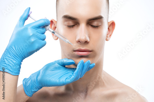 Men s cosmetology. Beautician makes a man a rejuvenation injection procedure on his face.