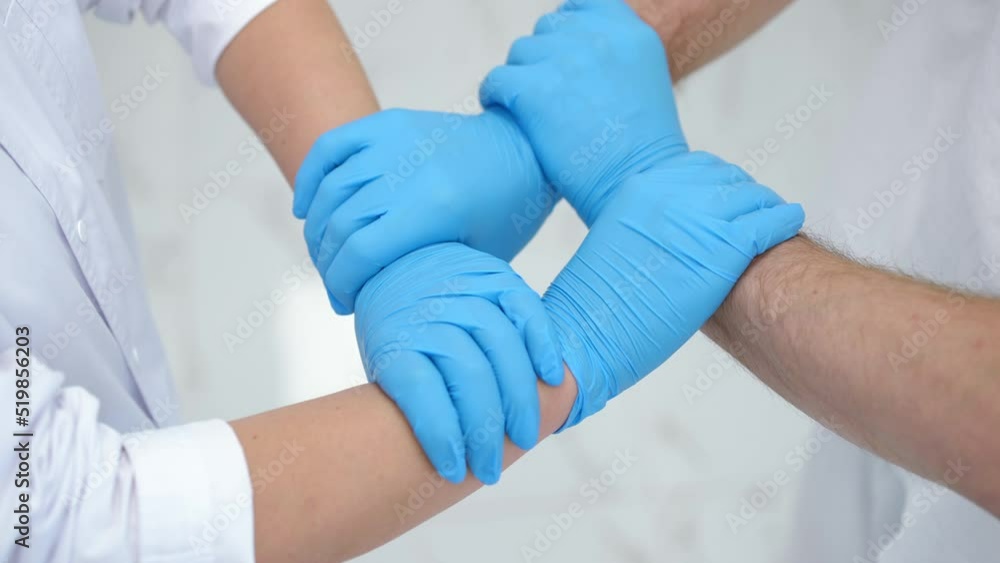 Close-up unrecognizable Caucasian doctor and nurse holding hands in square gesture indoors. Man and woman in disposable surgical gloves supporting endorsing each other. Medicine and lifestyle Close-up unrecognizable Caucasian doctor and nurse holding hands in square gesture indoors. Man and woman in disposable surgical gloves supporting endorsing each other. Medicine and lifestyle