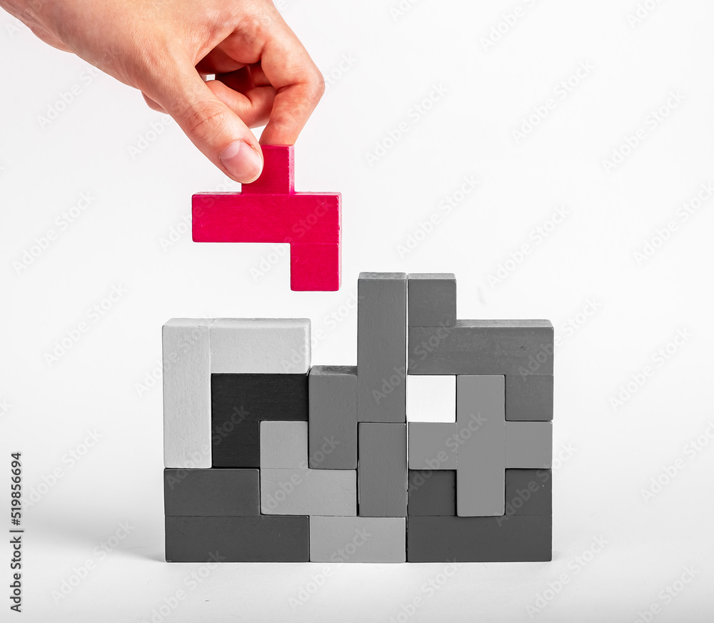 Hand putting outstanding red element in tetris puzzle construction, searching appropriate place for detail. Construction, formation concept. Good idea. High quality photo Hand putting outstanding red element in tetris puzzle construction, searching appropriate place for detail. Construction, formation concept. Good idea. High quality photo