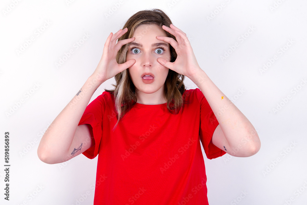 young caucasian woman wearing red T-shirt over white background keeping eyes opened to find a success opportunity. young caucasian woman wearing red T-shirt over white background keeping eyes opened to find a success opportunity.
