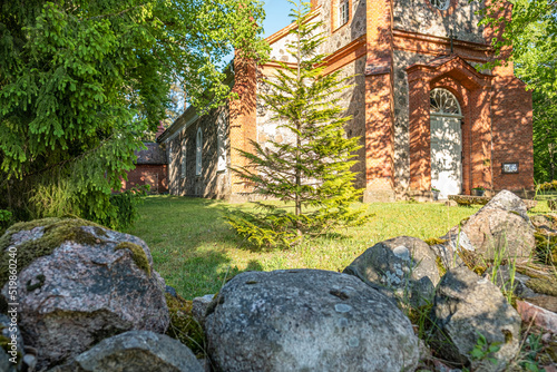 Impressive view of of the Evangelical Lutheran Church in Rida with blue sky in background and green trees and impressive boulders in the foreground. photo