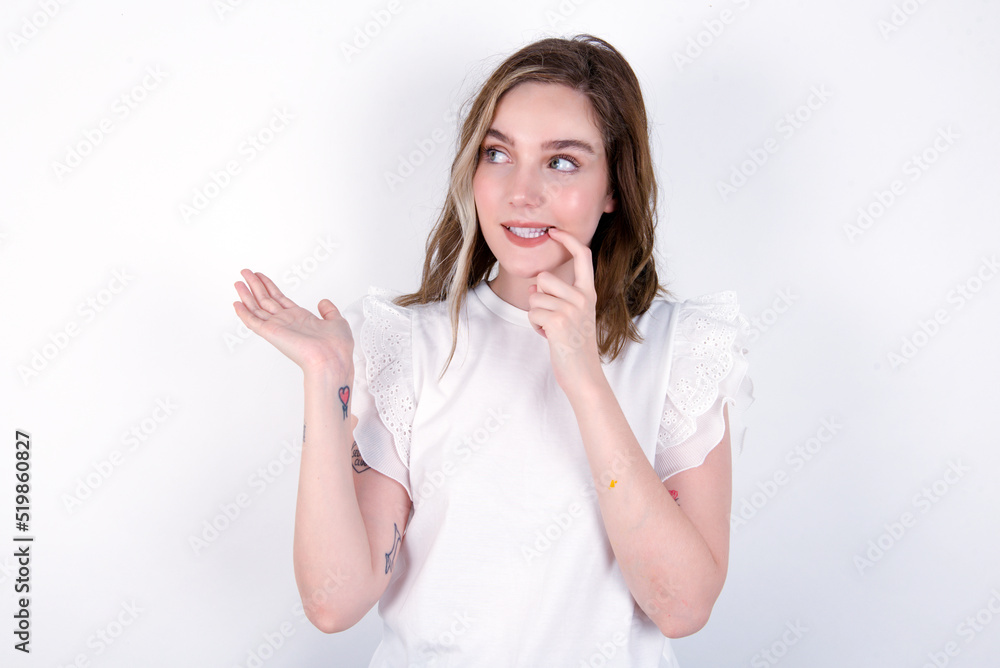 Positive young caucasian woman wearing white T-shirt over white background advert promo touch finger teeth Positive young caucasian woman wearing white T-shirt over white background advert promo touch finger teeth