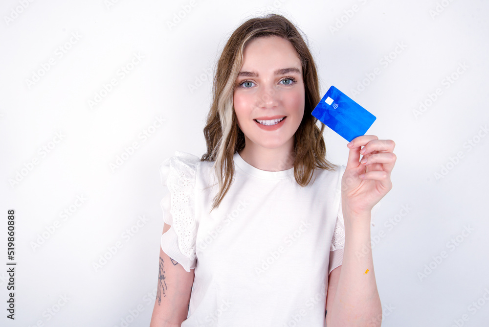 Photo of happy cheerful smiling positive young caucasian woman wearing white T-shirt over white background recommend credit card Photo of happy cheerful smiling positive young caucasian woman wearing white T-shirt over white background recommend credit card