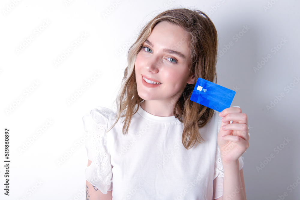 Close up photo of optimistic young caucasian woman wearing white T-shirt over white background hold card Close up photo of optimistic young caucasian woman wearing white T-shirt over white background hold card