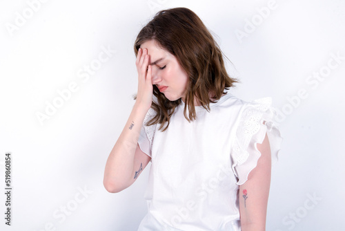 young caucasian woman wearing white T-shirt over white background with sad expression covering face with hands while crying. Depression concept.