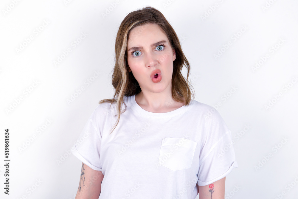 young caucasian woman wearing white T-shirt over white background expressing disgust, unwillingness, disregard having tensive look frowning face, looking indignant with something. young caucasian woman wearing white T-shirt over white background expressing disgust, unwillingness, disregard having tensive look frowning face, looking indignant with something.