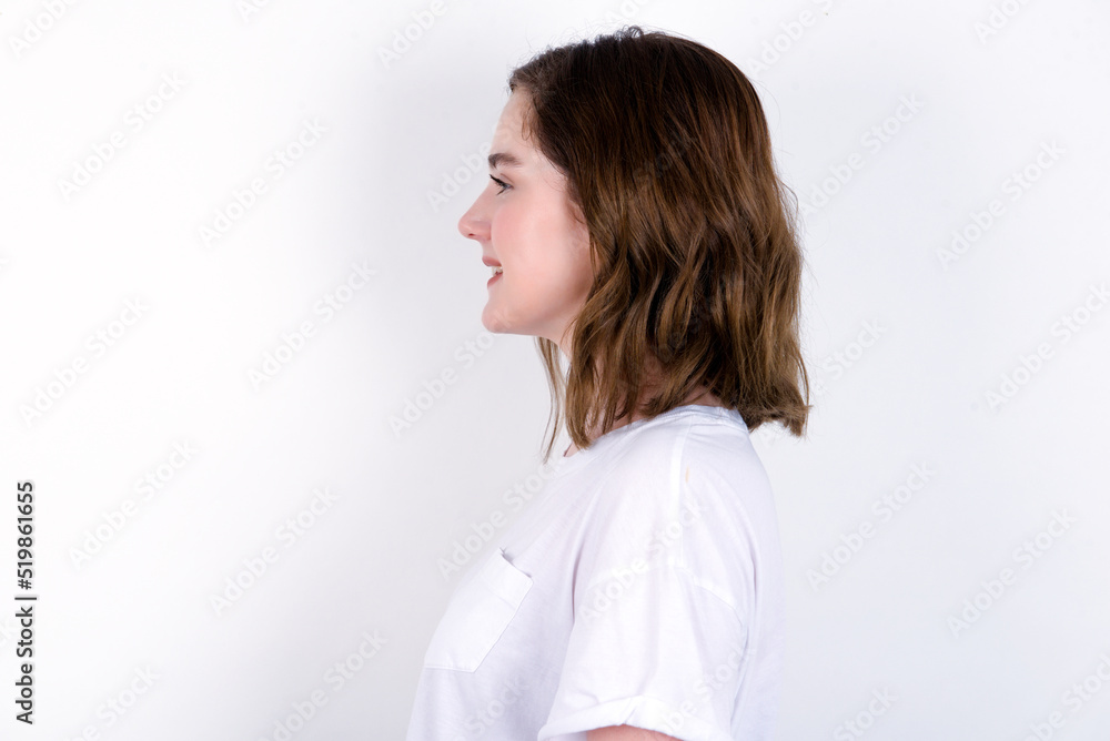Profile of smiling young caucasian woman wearing white T-shirt over white background with healthy skin, has contemplative expression, ready to have outdoor walk. Profile of smiling young caucasian woman wearing white T-shirt over white background with healthy skin, has contemplative expression, ready to have outdoor walk.
