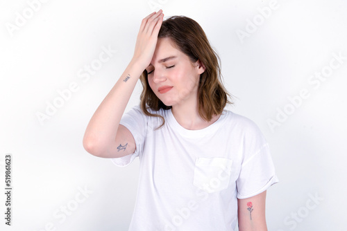 Wallpaper Mural Frustrated young caucasian woman wearing white T-shirt over white background holding hand on forehead being depressed regretting what he did having headache, looking stressful. Torontodigital.ca